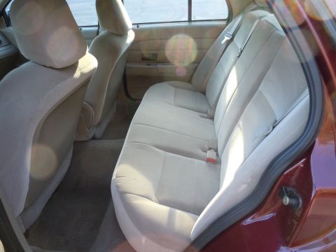 2001 Ford Crown Victoria - The interior of a maroon 2001 Ford Crown Victoria is visible from the rear passenger side door.