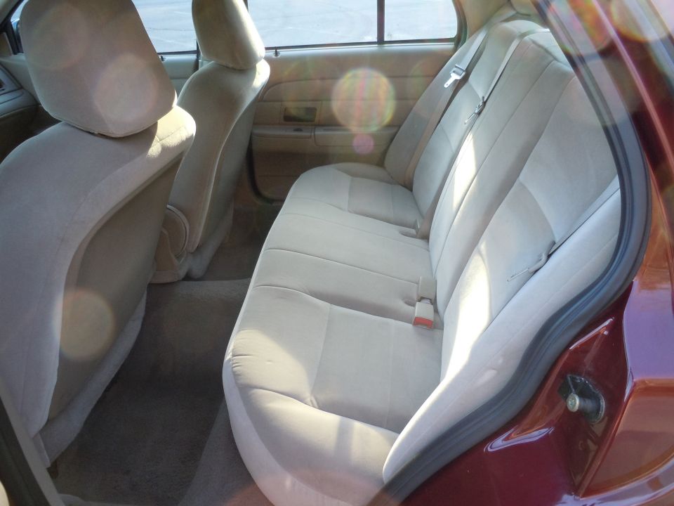 Interior of a maroon 2001 Ford Crown Victoria showing the rear bench seat and door panel