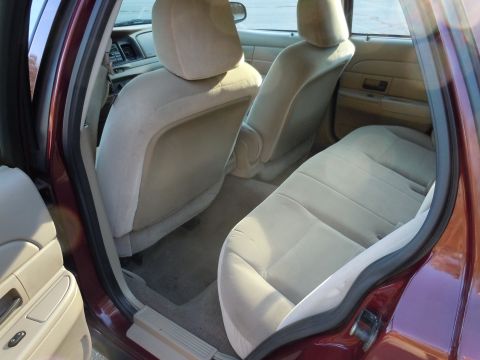 2001 Ford Crown Victoria - Rear interior view of a maroon 2001 Ford Crown Victoria, showing the cloth seats and door panel.