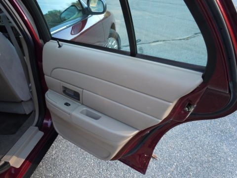 2001 Ford Crown Victoria - The interior door panel of a 2001 Ford Crown Victoria is visible, with a reflection of another vehicle in the rear window.