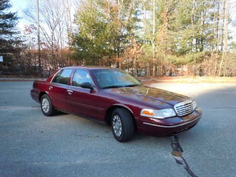 2001 Ford Crown Victoria - A maroon 2001 Ford Crown Victoria is parked outside on a paved surface with trees in the background.