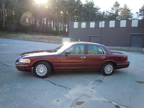 2001 Ford Crown Victoria - A maroon 2001 Ford Crown Victoria is parked outside a commercial building on a sunny day.