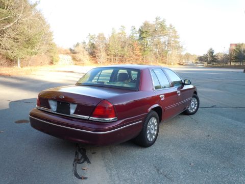 2001 Ford Crown Victoria - Rear three-quarter view of a maroon 2001 Ford Crown Victoria sedan on a paved surface.