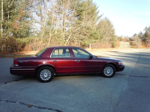 2001 Ford Crown Victoria - A maroon Ford Crown Victoria is parked outside on a sunny day.