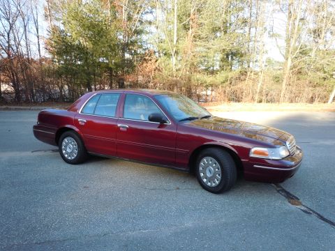 2001 Ford Crown Victoria - A maroon Ford Crown Victoria is parked on an asphalt surface with trees in the background.