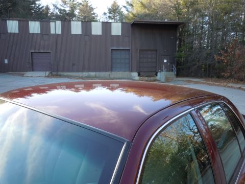 2001 Ford Crown Victoria - Reflection on the car's roof shows a brown building with garage doors and surrounding trees.