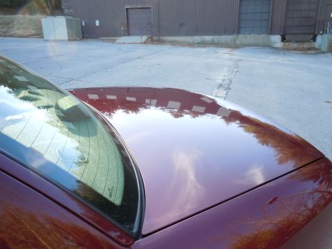 2001 Ford Crown Victoria - The reflection on the car's surface shows a building with multiple windows and surrounding trees.