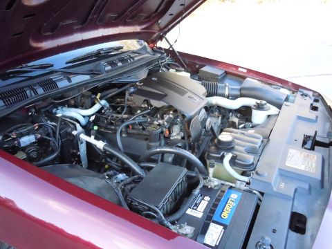 2001 Ford Crown Victoria - The engine bay of a maroon Ford Crown Victoria, showing the V8 engine, battery, and various hoses and components.