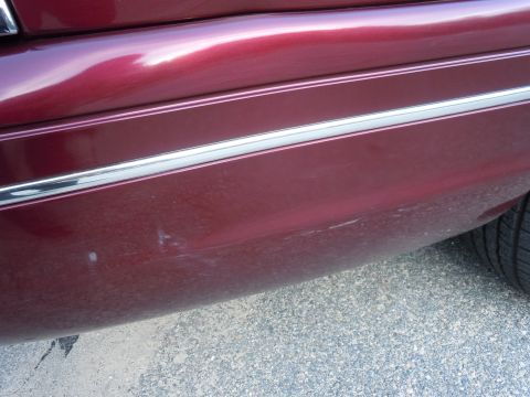 2001 Ford Crown Victoria - Close-up of a car's rear bumper corner showing damage and a tire.