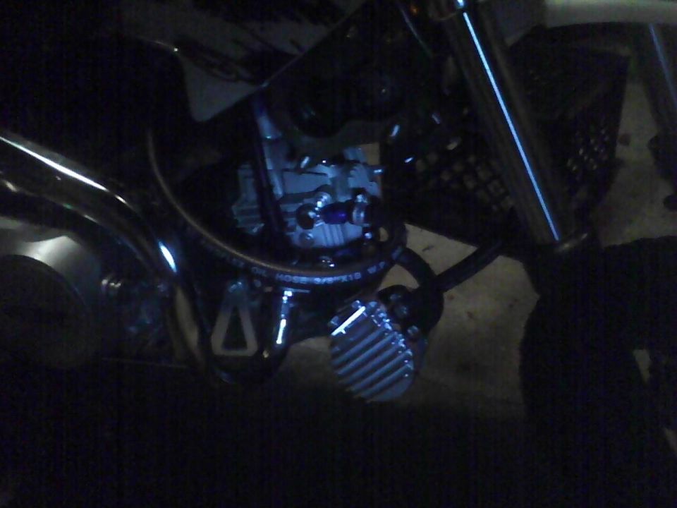 Close-up of a motorcycle's engine and exhaust system, showing hoses and some metal components