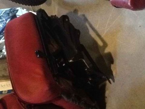 1985 Ford Bronco - A red car seat with a black metal frame is shown, possibly for a vehicle.