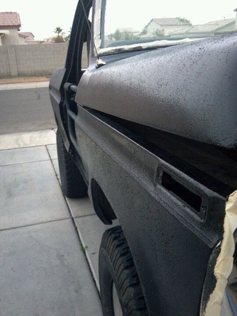 1978 Ford Bronco - Side view of a 1978 Ford Bronco fender and open door, showing textured black paint.