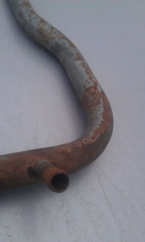 1991 Ford Festiva - A close-up view of a rusted metal pipe, likely an exhaust or coolant component, with a small side outlet. The Supermotors.net logo is visib…