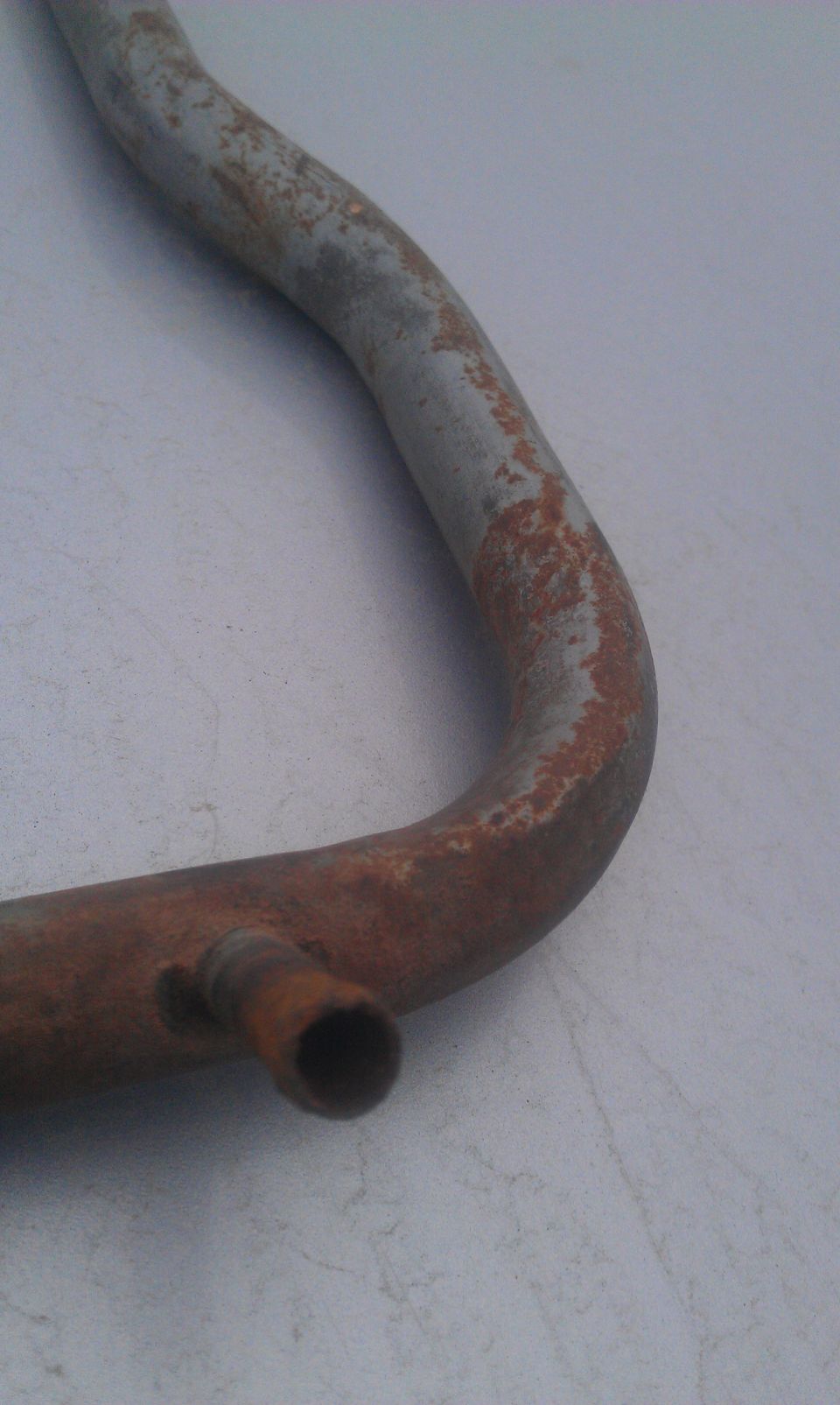 Rusted metal pipe with a small outlet, Supermotors.net logo visible