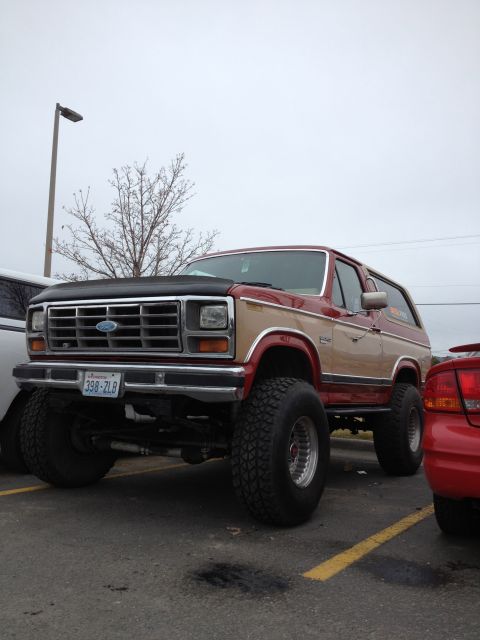 1984 Ford Bronco - This lifted Ford Bronco features a two-tone red and tan paint scheme and aggressive off-road tires.