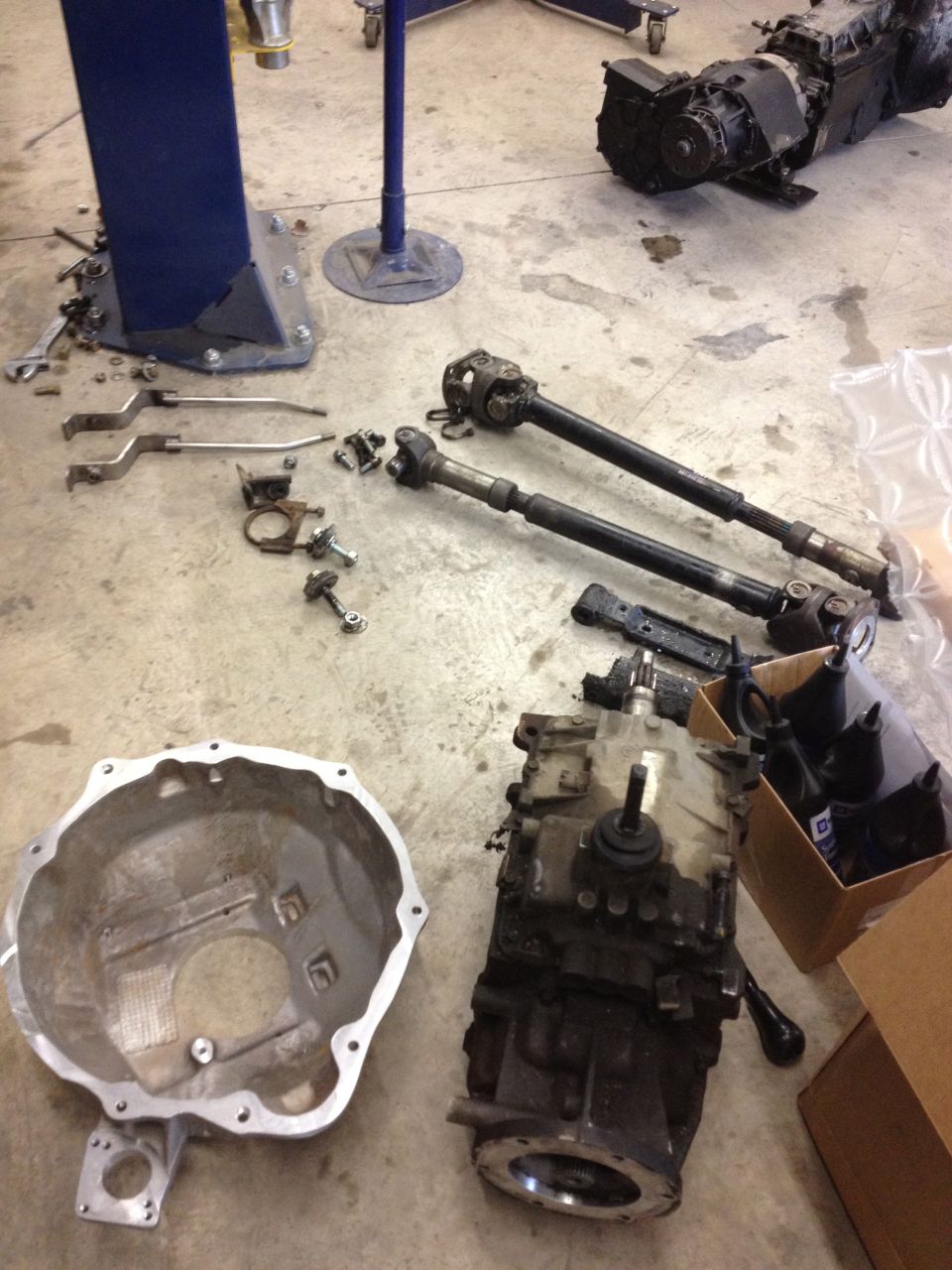 Transmission, bell housing, and driveshafts laid out on concrete floor