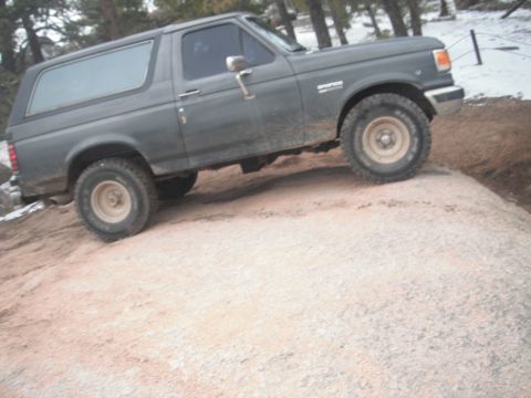 1990 Ford Bronco - This 1990 Ford Bronco is navigating a challenging rocky trail in a wooded area.