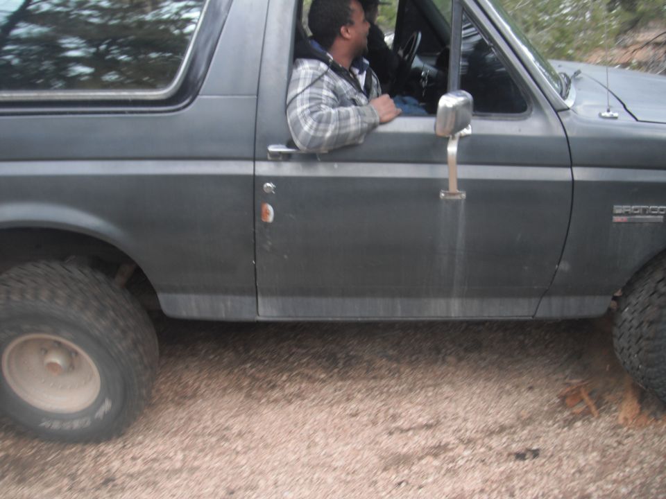 Gray 1990 Ford Bronco side view, driver's door open, with a badge on the fender