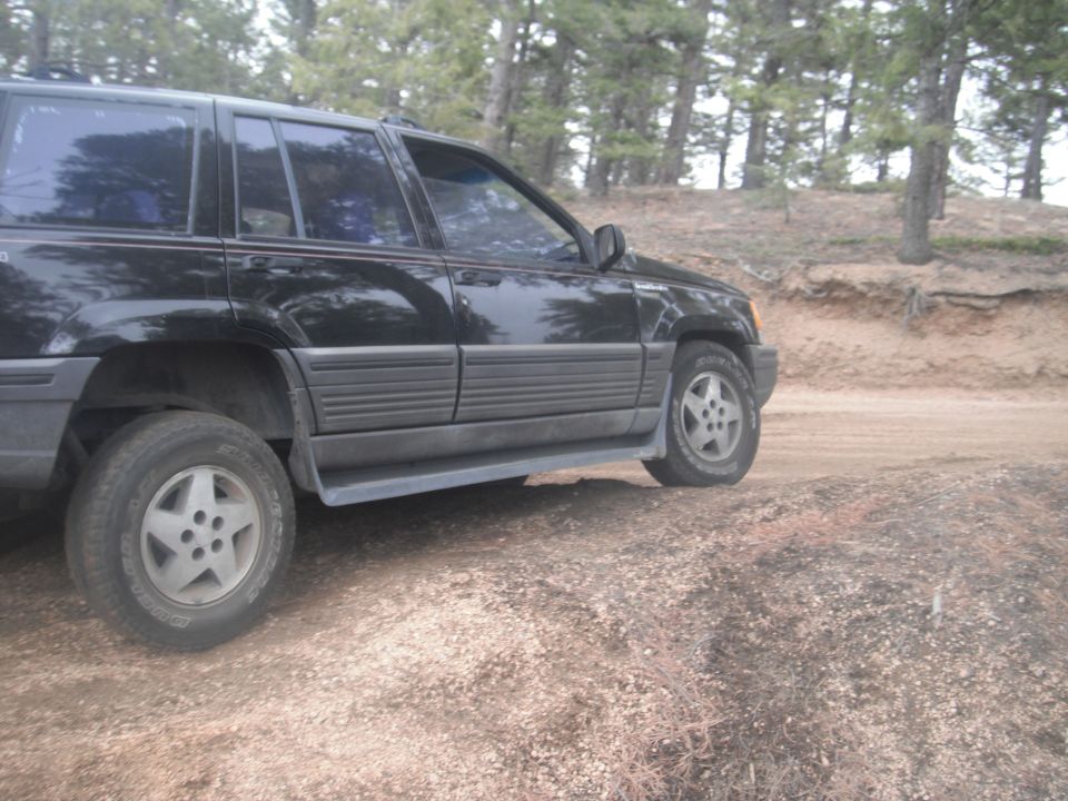 Black SUV parked on a dirt road with trees in the background