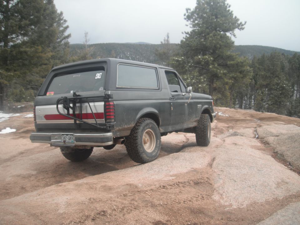 Ford Bronco parked on a rocky trail with trees in the background