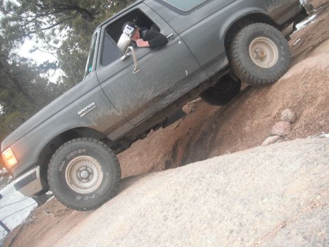 1990 Ford Bronco - A 1990 Ford Bronco navigates a rocky trail, demonstrating its off-road capabilities.
