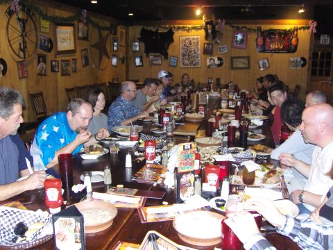 2007 Ford Mustang - A group of people are seated at a long table in a restaurant, enjoying a meal together. The table is laden with food, drinks, and menus.
