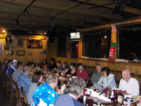 2007 Ford Mustang - A group of people are seated at a long table for a Christmas party dinner, with decorations visible in the background.