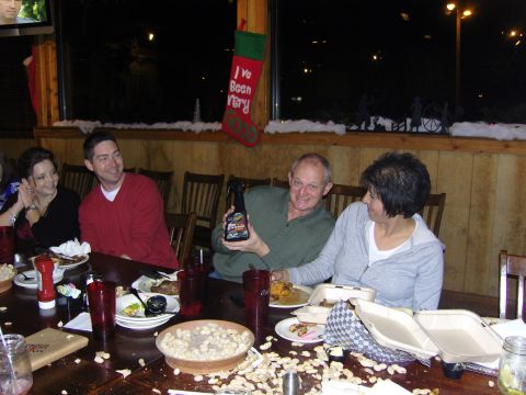 2007 Ford Mustang - A group of people are seated at a table laden with food and drinks, with peanut shells scattered across the surface.