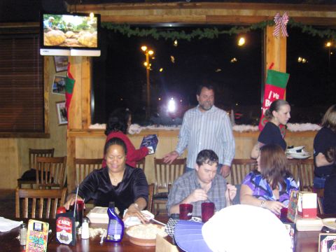 2007 Ford Mustang - A group of people are celebrating Christmas at a restaurant, with festive decorations adorning the space.