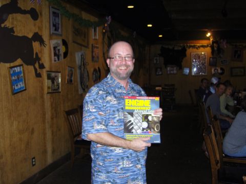2007 Ford Mustang - A man smiles while holding a magazine at a gathering.