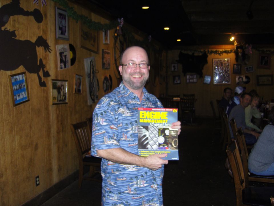 Man in a blue Hawaiian shirt holds a magazine titled "Engine Management Advanced Tuning"