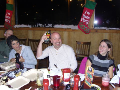 2007 Ford Mustang - A group of people are gathered around a table, enjoying a meal and drinks during a Christmas celebration.