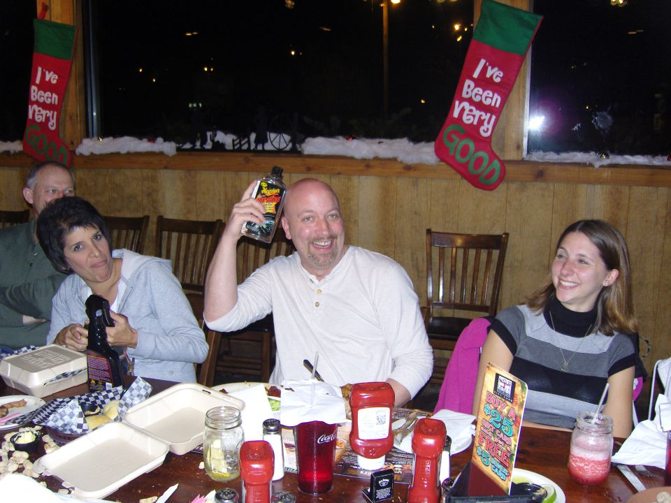 People sitting at a table with food and drinks, with Christmas stockings hanging in the background