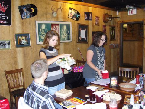 2007 Ford Mustang - A group of people are gathered around a table in a room with wood-paneled walls and various decorations.