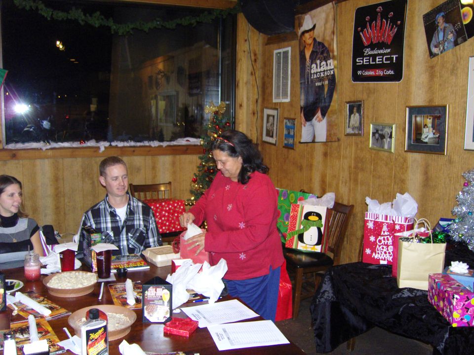 People gathered around a table with Christmas gifts and decorations, with posters on the wall