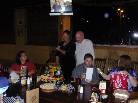 2007 Ford Mustang - A group of people are celebrating at a Christmas party, with food and gifts on the table.
