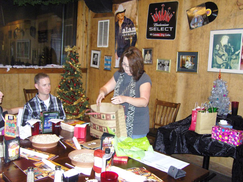 People gathered around a table with Christmas gifts and decorations, with posters on the wall