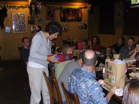 2007 Ford Mustang - A group of people are gathered around a table, possibly for a holiday celebration, as a woman presents a Ford branded box.