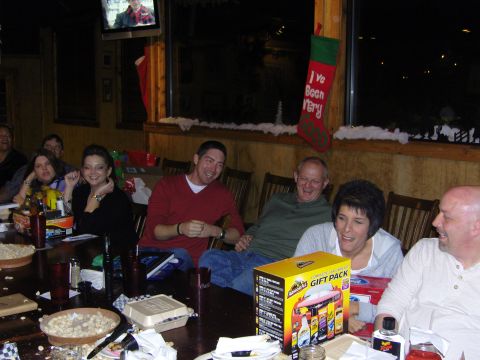 2007 Ford Mustang - A group of people are gathered around a table, with a gift pack and Christmas decorations visible.