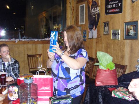 2007 Ford Mustang - A woman smiles while holding a gift at a holiday gathering, with presents and decorations visible.
