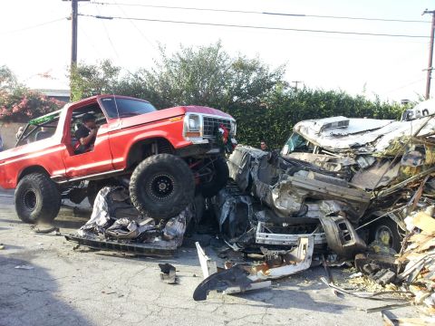 1978 Ford Bronco - A red 1978 Ford Bronco is perched atop a mangled white vehicle after a collision.