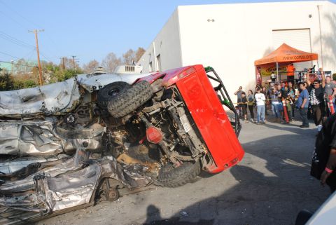 1978 Ford Bronco - A red 1978 Ford Bronco lies on its side after an apparent crash, with onlookers gathered around.