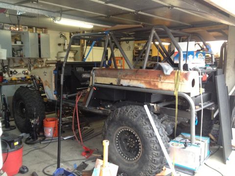 1961 International Scout 800 - Custom off-road vehicle build in progress, a prominent roll cage and large tires.