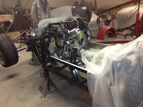 1975 Ford Ranchero - A vehicle chassis is being assembled in a workshop, with parts covered in plastic.