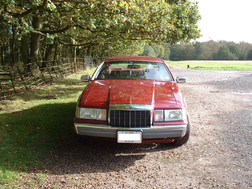 Red 1992 Lincoln Mark VII parked outdoors under trees