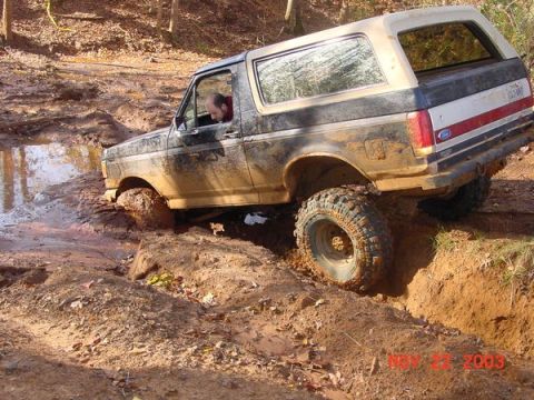 1989 Ford Bronco - A 1989 Ford Bronco tackles a challenging muddy obstacle on an off-road trail.