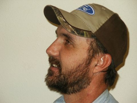 1990 Ford Bronco - A man is shown in profile wearing a baseball cap with a Ford logo and camouflage accents.