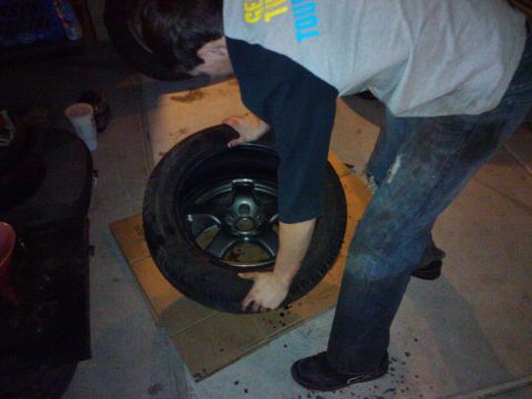 1995 Ford Probe - A person is holding a car wheel, which is resting on a piece of cardboard.