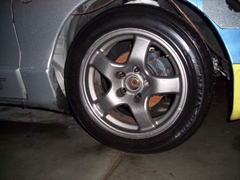 1995 Ford Probe - A close-up view of a silver five-spoke wheel and blue brake caliper on a vehicle.