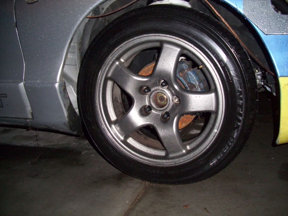 Close-up of a silver five-spoke wheel with a blue brake caliper